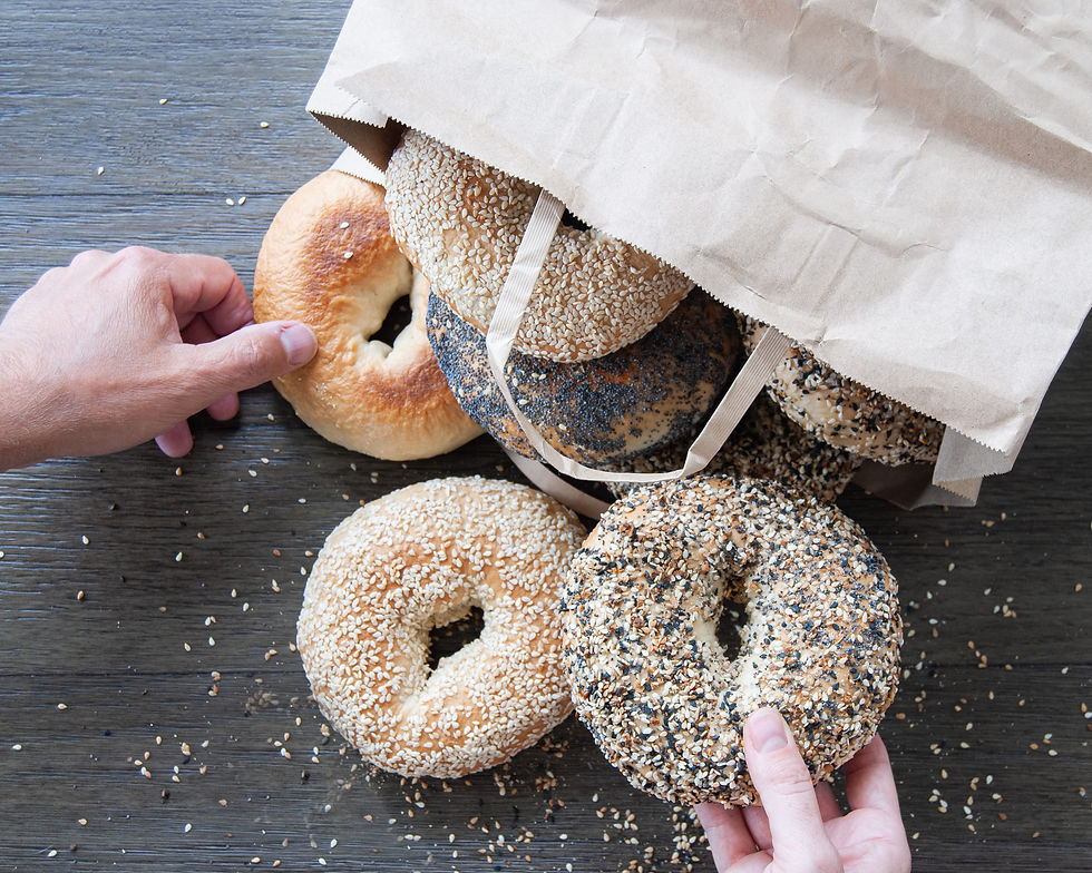 Bagels being pulled out of a paper bag by two hands.jpg